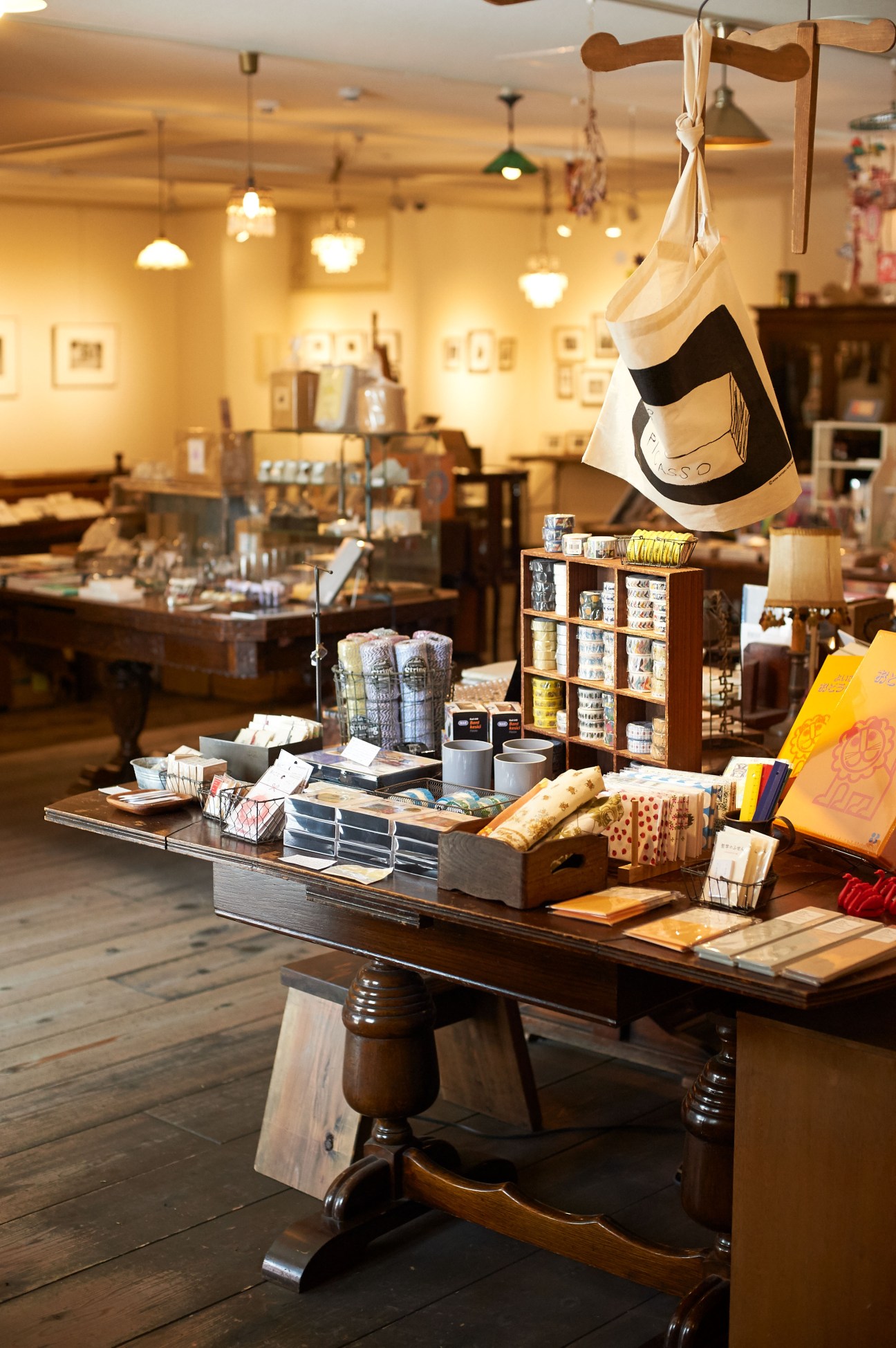 Interior of a Kyoto craft shop displaying handmade ceramics, washi paper, textiles, and wooden accessories on wooden display tables and shelves.