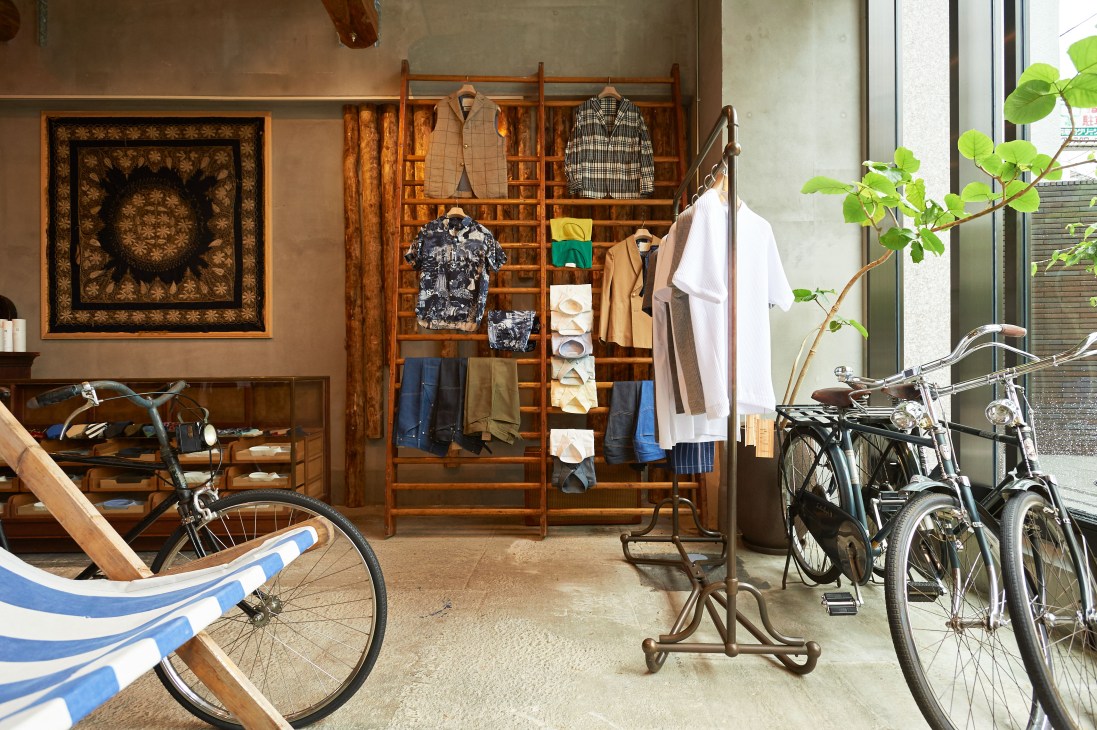 Interior of Franklin Tailored menswear shop in Kyoto displaying clothing on wooden display racks and bicycles.