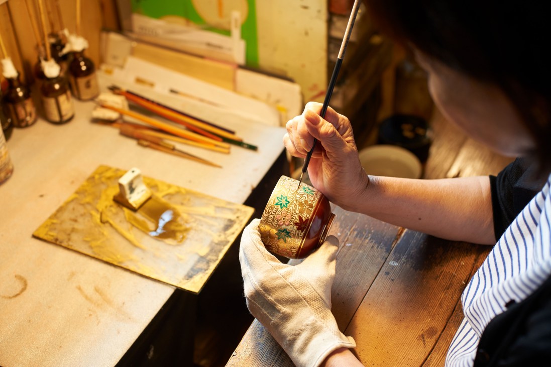 Artisan hand-paints decorative details on a ceramic vessel at Tosai kiln in Kyoto.