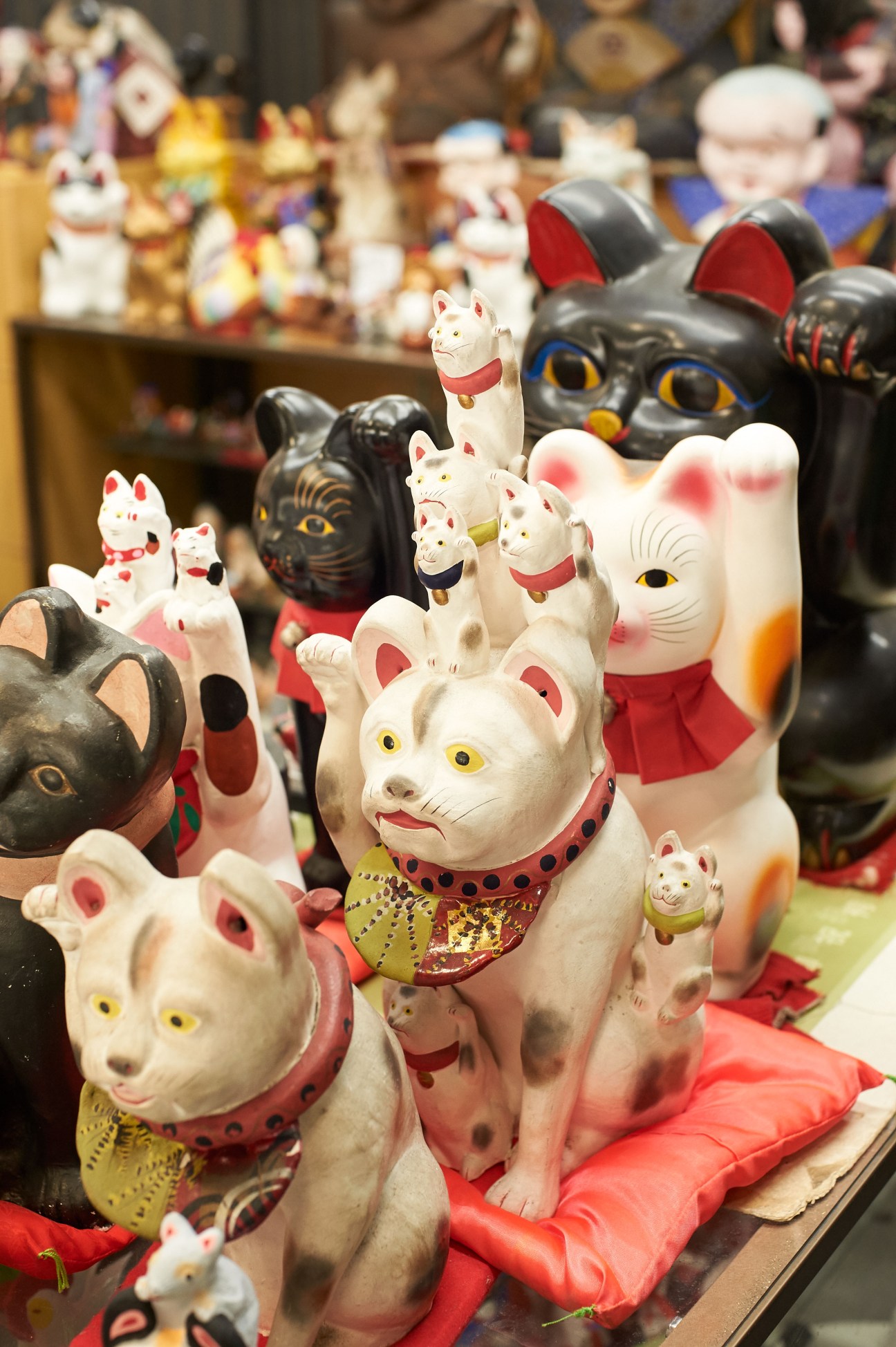Collection of white and black ceramic maneki-neko cat figurines with red accents displayed in rows.