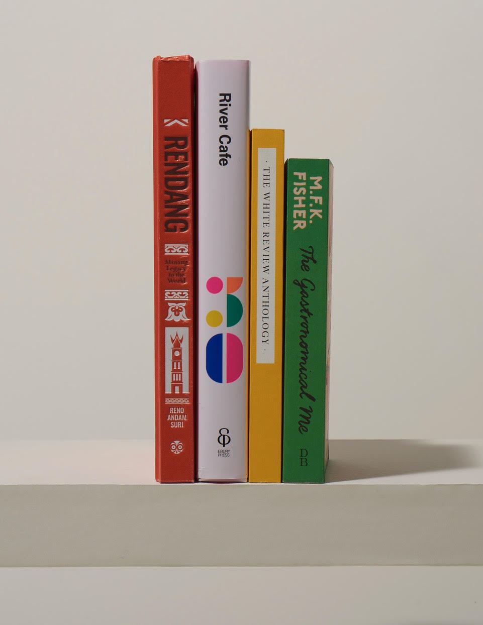 Four colorful book spines arranged vertically including Rendang, River Cafe, MFK Fisher, and other titles.