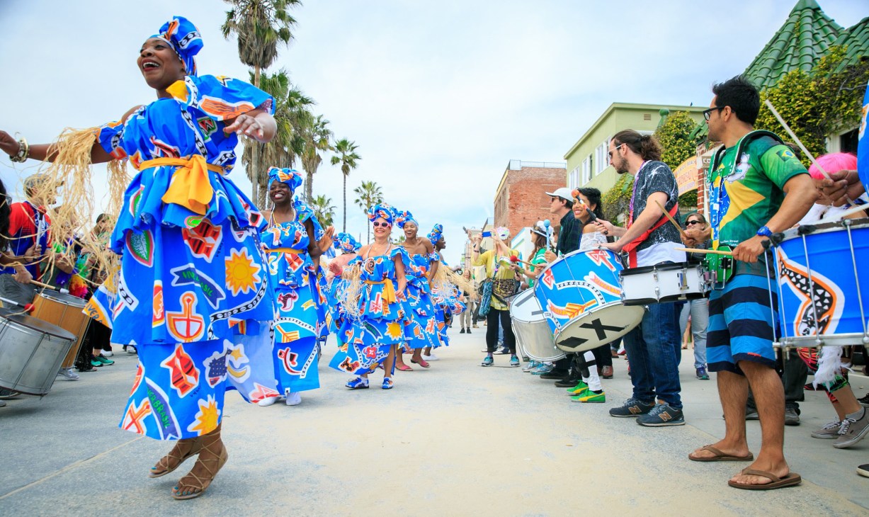 Colorful carnival parade with performers in vibrant blue and patterned costumes dancing in a street.