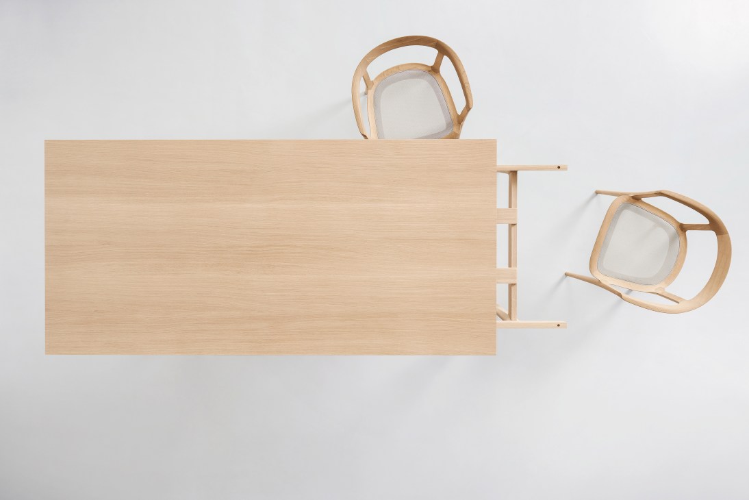 Overhead view of a light wood dining table with elegant curved legs and an extended leaf.