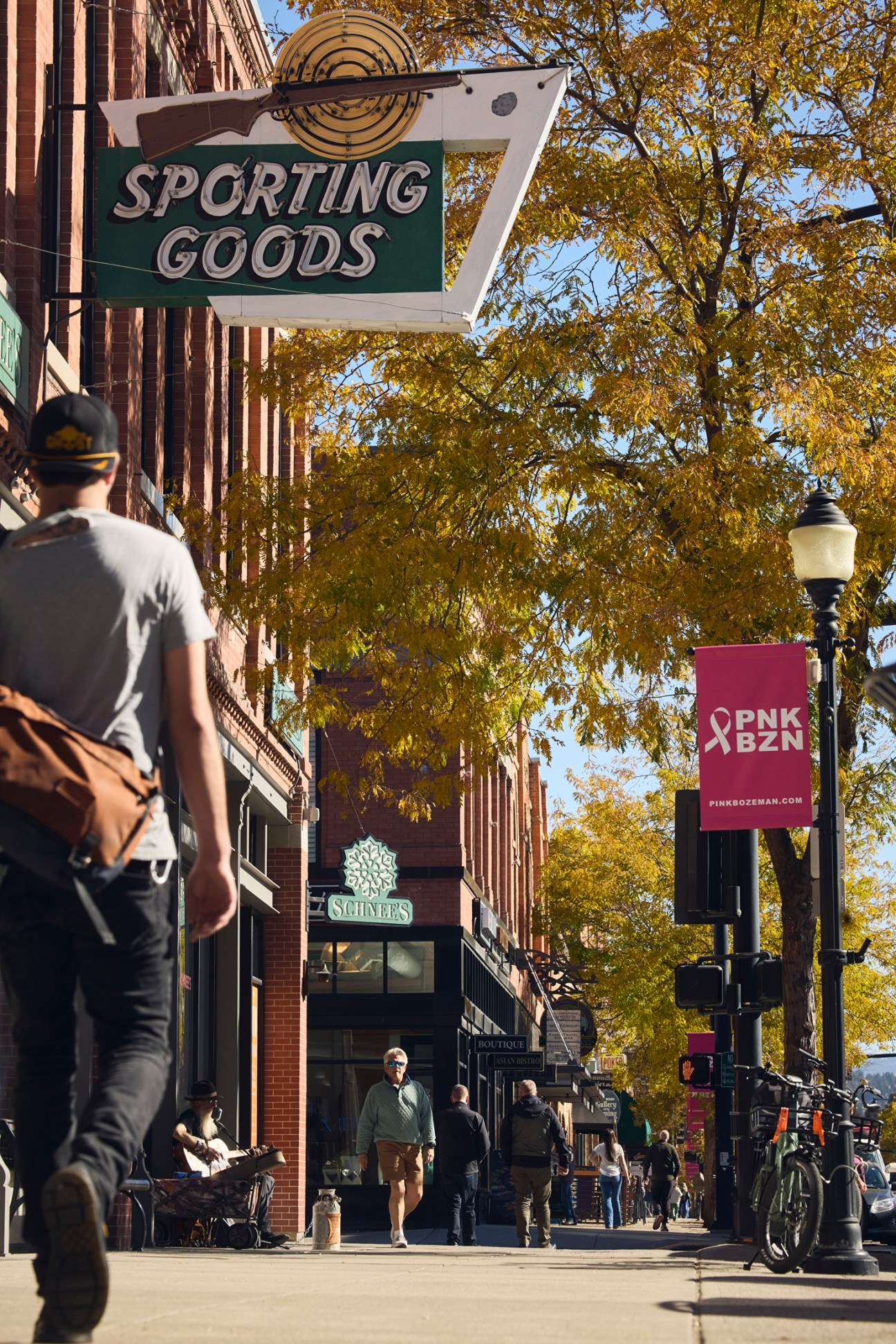 Pedestrian street in Bozeman with vintage Sporting Goods sign and autumn foliage.