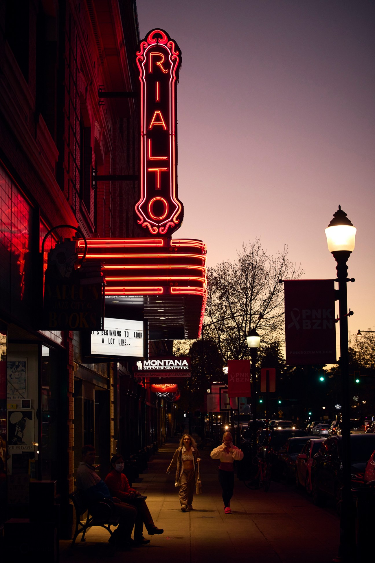 The Rialto neon sign glows red above a downtown street at dusk in Bozeman, Montana.