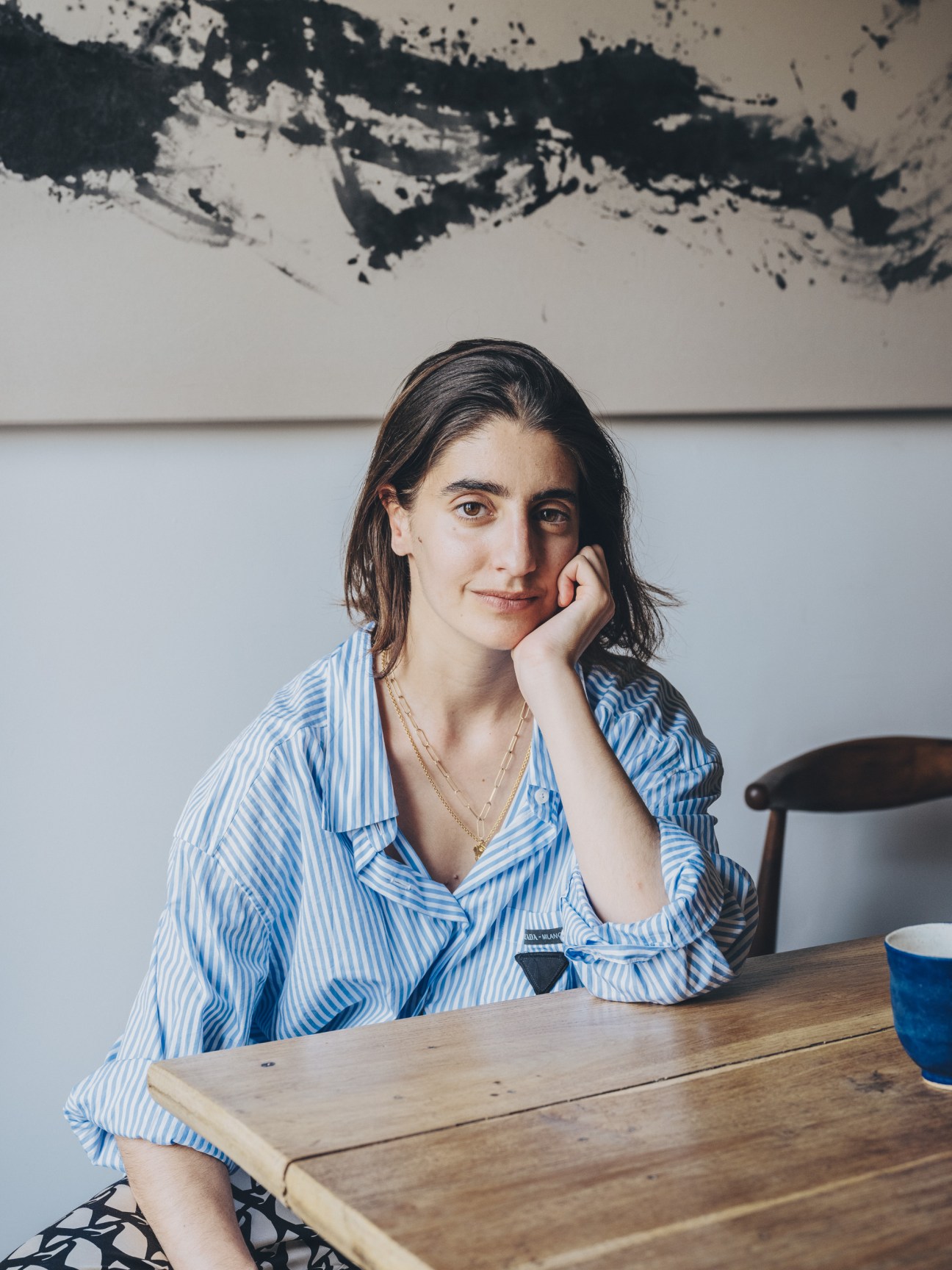 Clara Diez, co-founder of Formaje cheese shop, sitting at wooden table in blue striped shirt