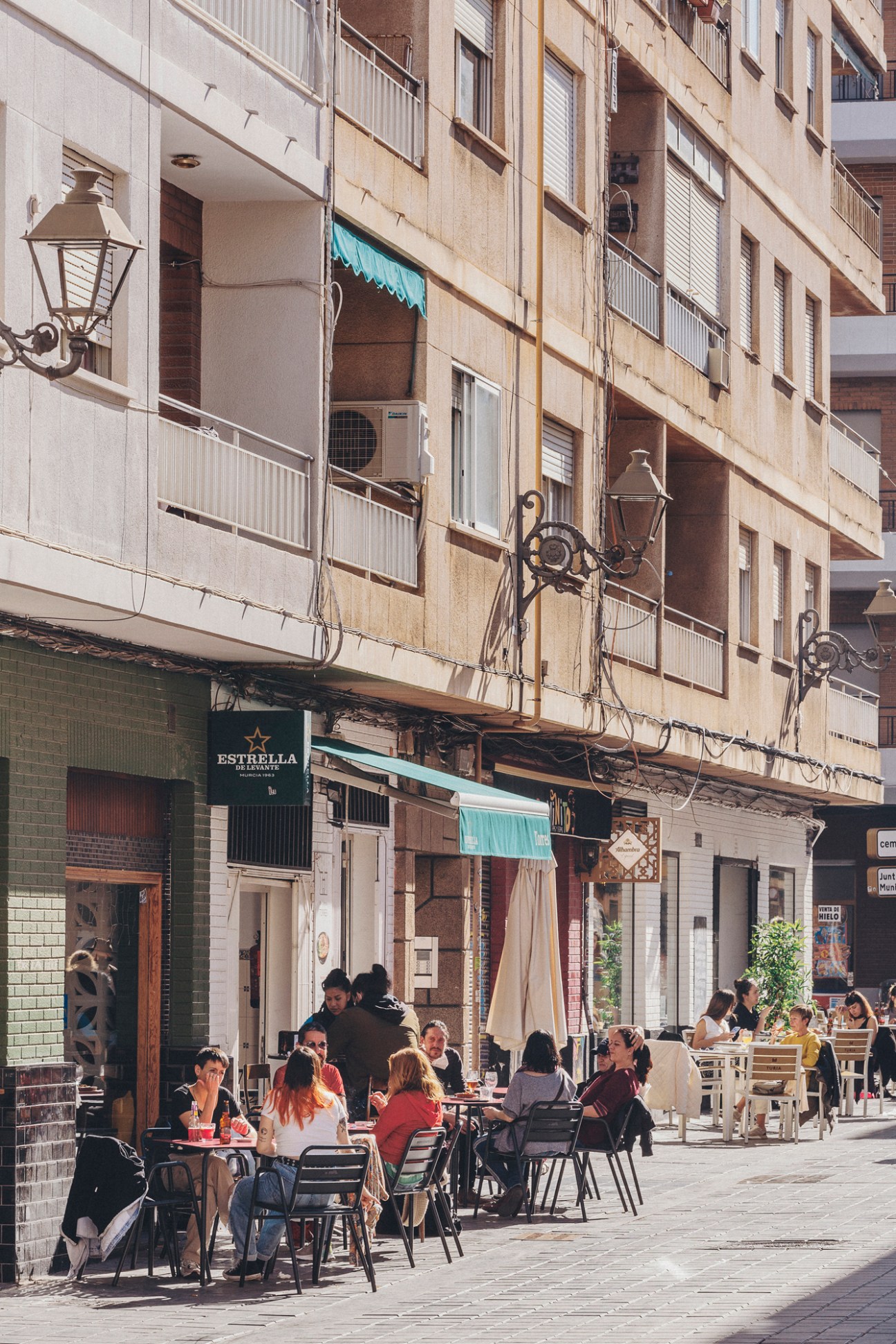 People enjoying drinks at outdoor cafe tables during afternoon hours