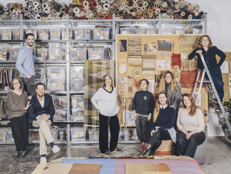 Nani Marquina team members posing in their Barcelona studio surrounded by fabric rolls and rug samples