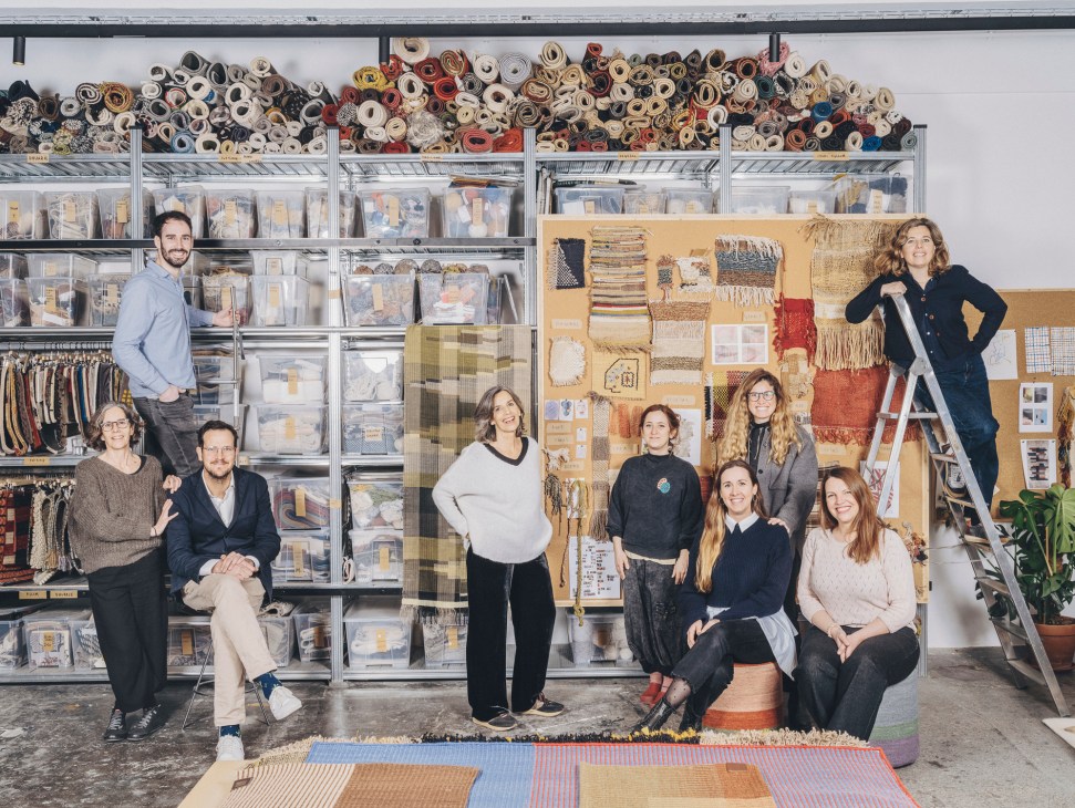Nani Marquina team members posing in their Barcelona studio surrounded by fabric rolls and rug samples