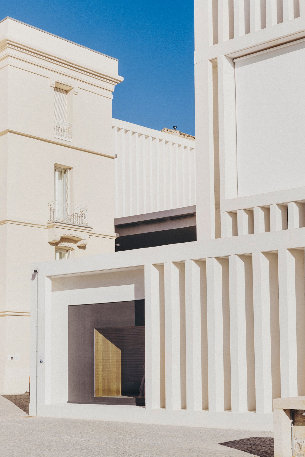 White modern museum building with vertical slats and geometric architecture against blue sky