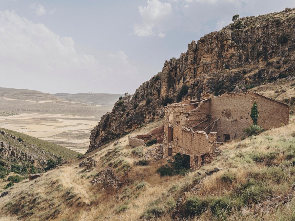 Abandoned stone buildings with deteriorating walls and overgrown vegetation in the deserted village of Pardos