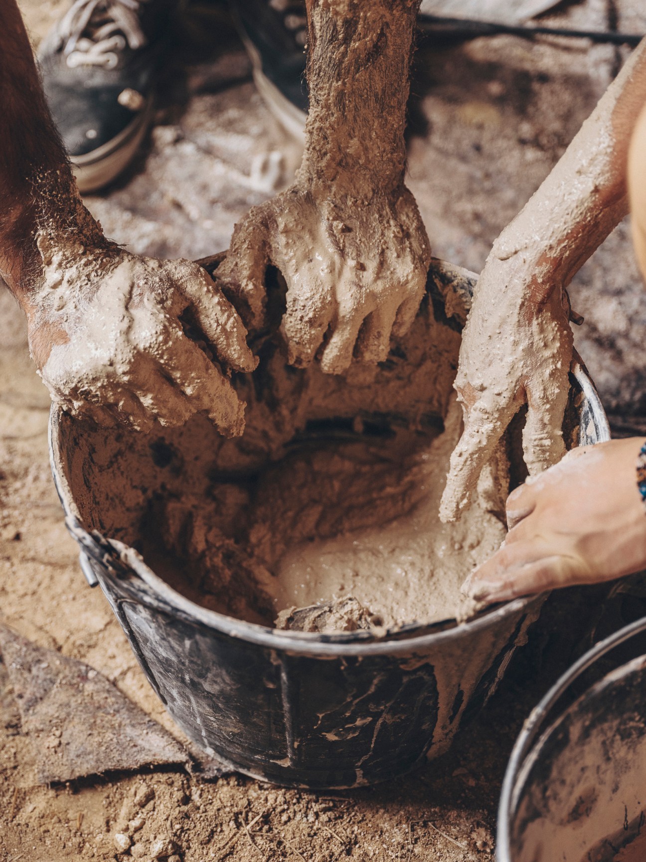 Hands covered in gypsum plaster working with traditional building materials during restoration workshop
