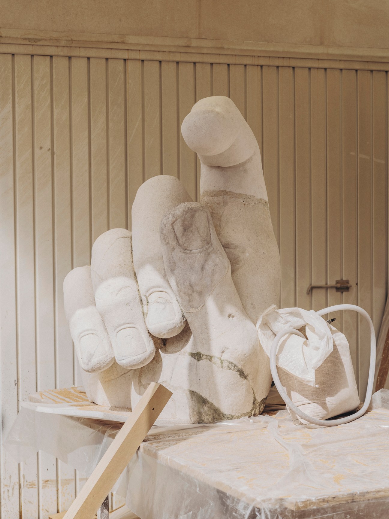 Large stone hand sculpture with detailed finger carving in workshop setting
