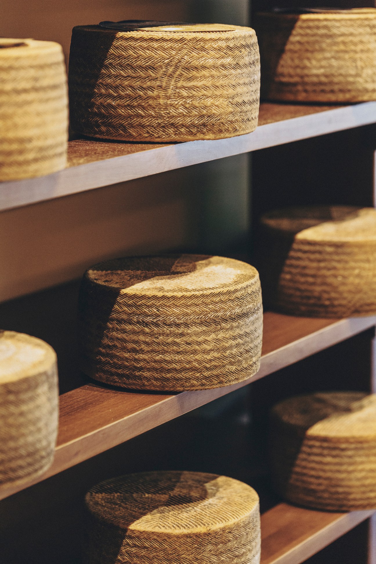 Wheels of aged cheese arranged on wooden shelves at Formaje cheese shop in Madrid