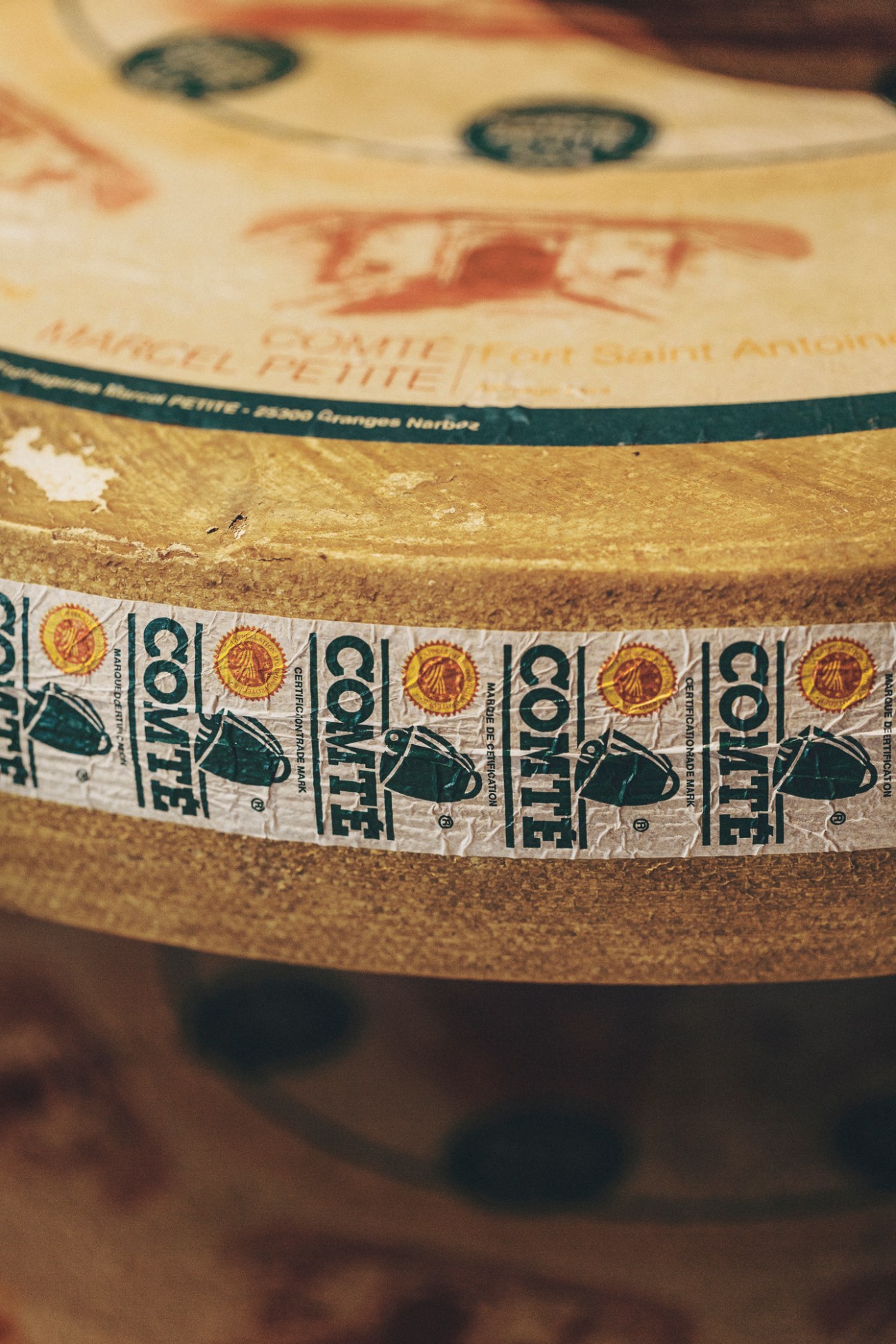 Wheels of comté and parmigiano-reggiano cheese arranged on wooden shelves at Formaje shop in Madrid