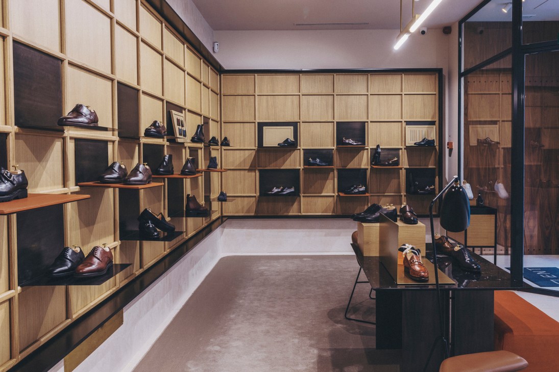 Modern shoe store interior with wooden modular shelving displaying dress shoes and leather footwear