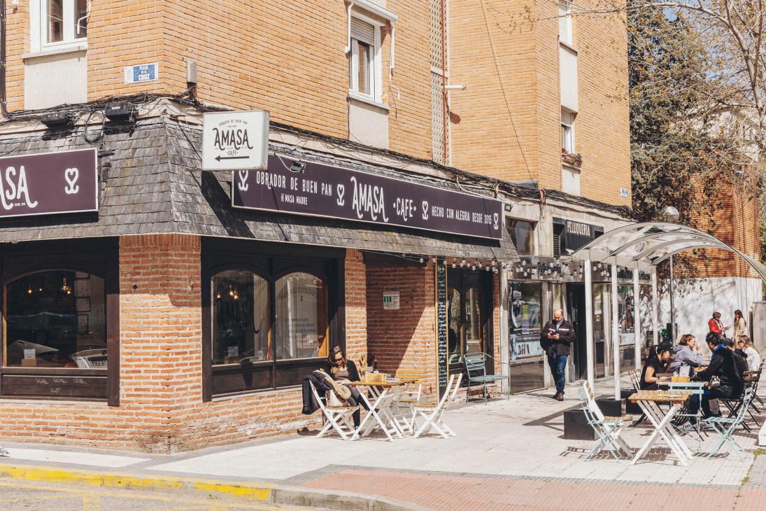 Outdoor seating area with people at tables outside Amasa bakery storefront