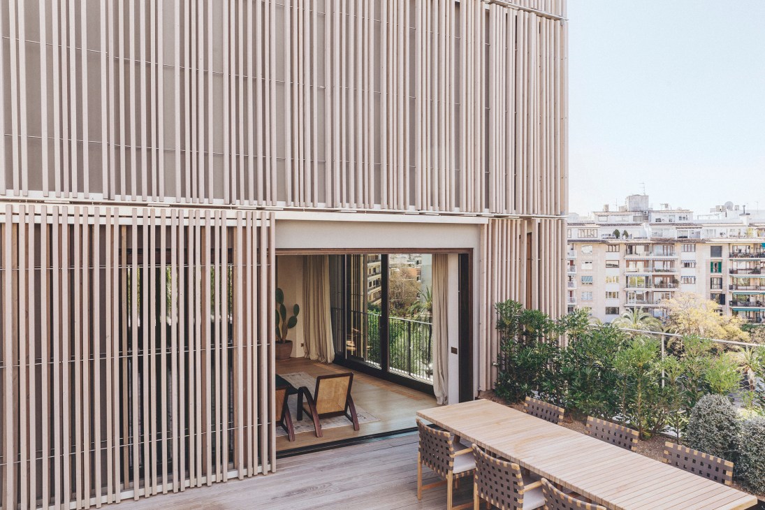Modern penthouse terrace with wooden deck, outdoor furniture, timber-slatted facade, and city view
