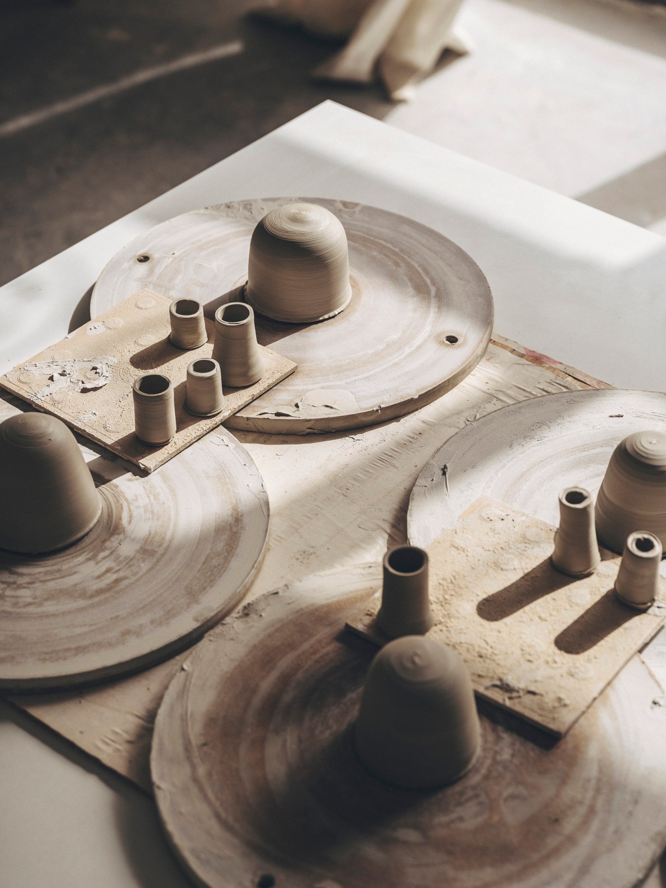 Various ceramic pieces including pots and vessels displayed on pottery wheels in Roberto Paparcone's studio