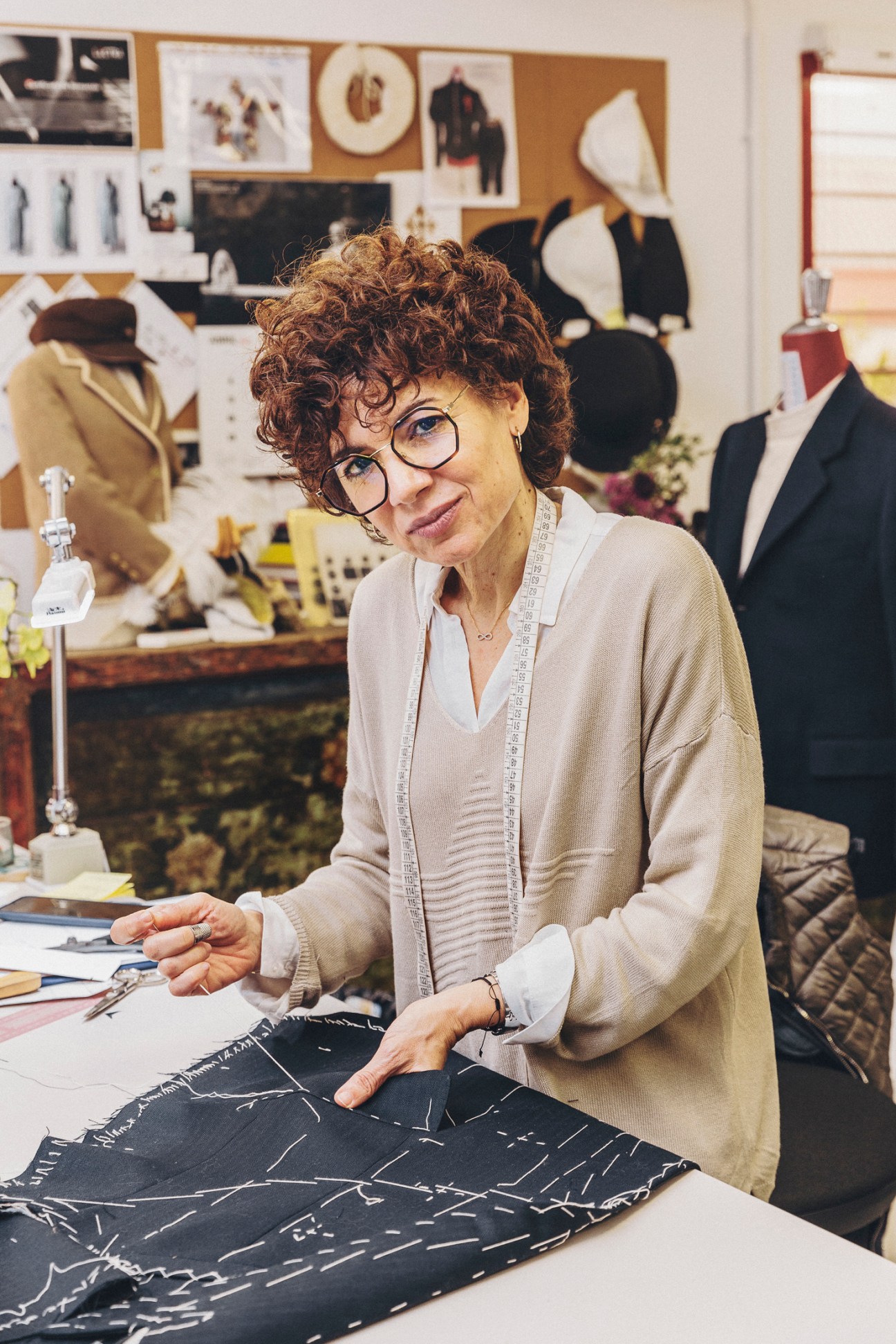 Dress-maker Maria José Moya working with fabric and measuring tape in costume workshop with mannequins and design boards