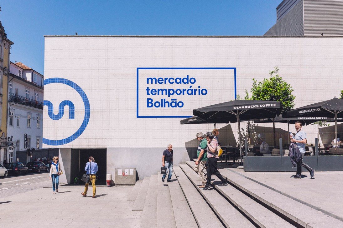 Temporary Mercado do Bolhão market building with blue signage and Starbucks umbrellas in Porto.