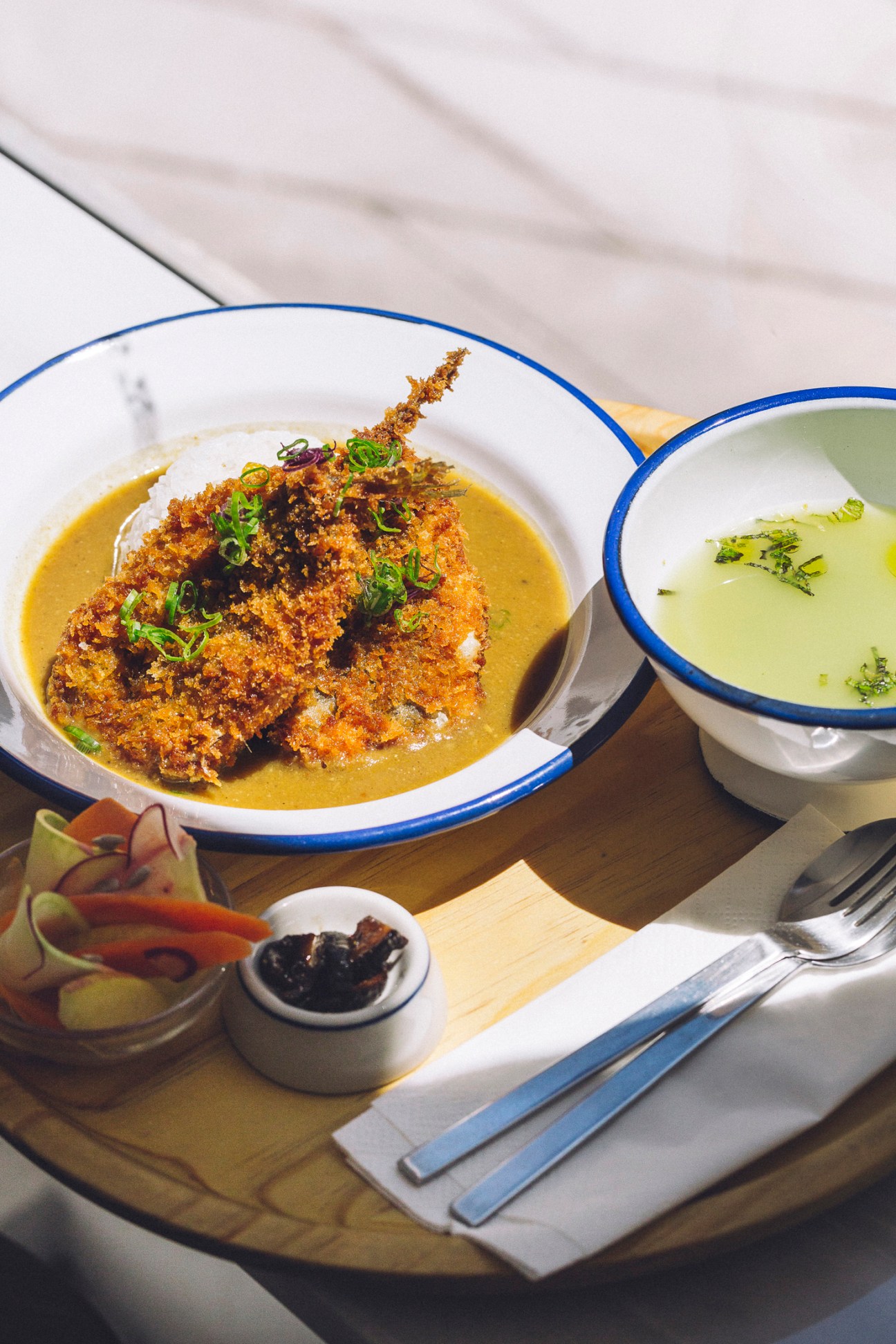 Plated Mediterranean dishes at Namban Oporto Kitchen in Porto, featuring crispy topped soup and herb-garnished sauce.