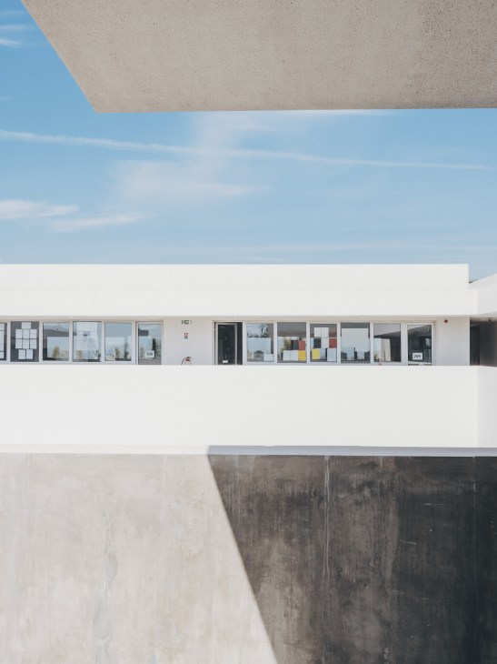 Horizontal lines and geometric details of the school's modernist white facade against blue sky