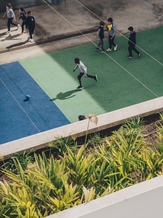 Students playing with a ball in a bright courtyard area of the school