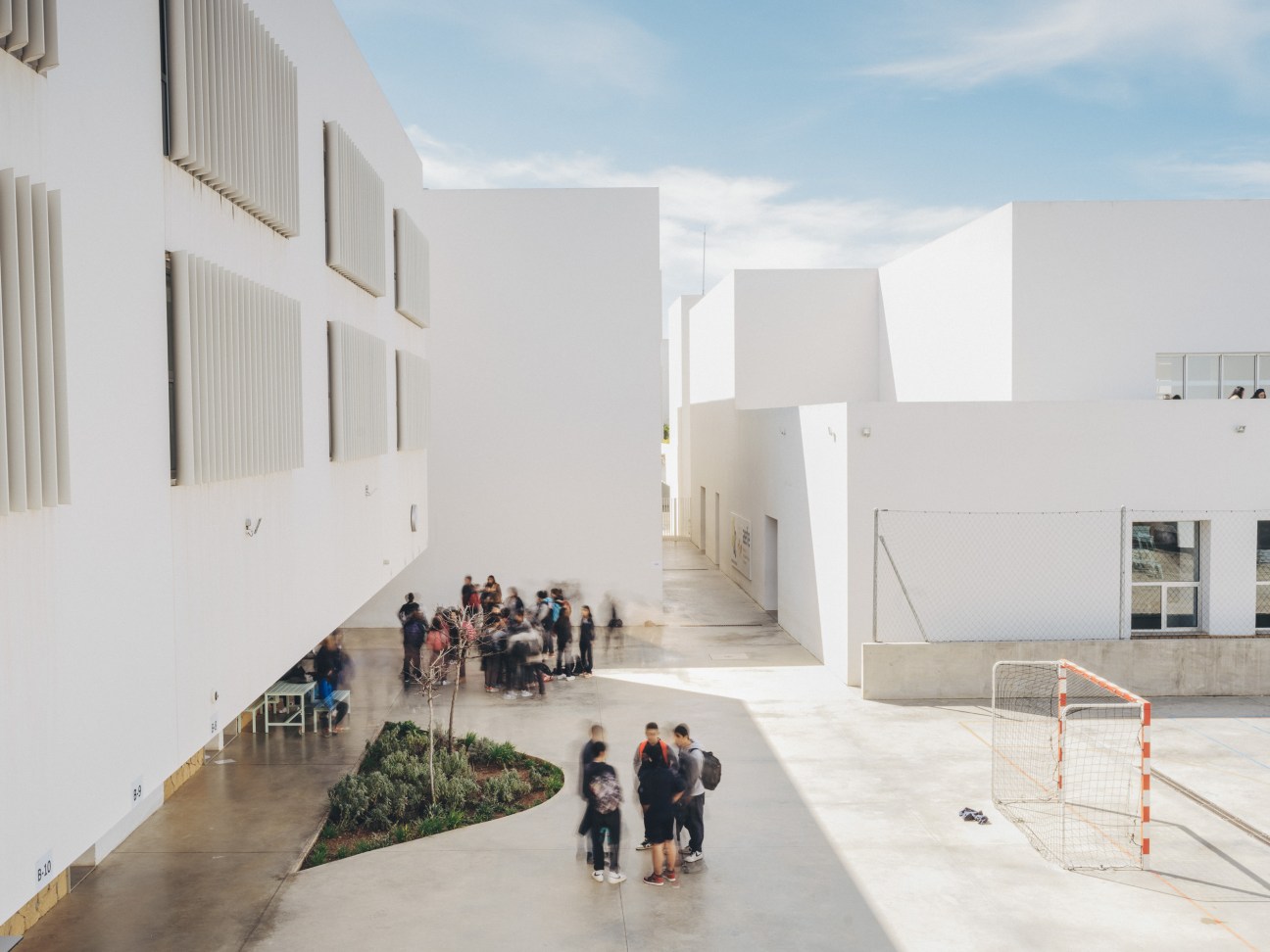 Outdoor terrace area showing the school's open design philosophy with white architectural elements and blue sky