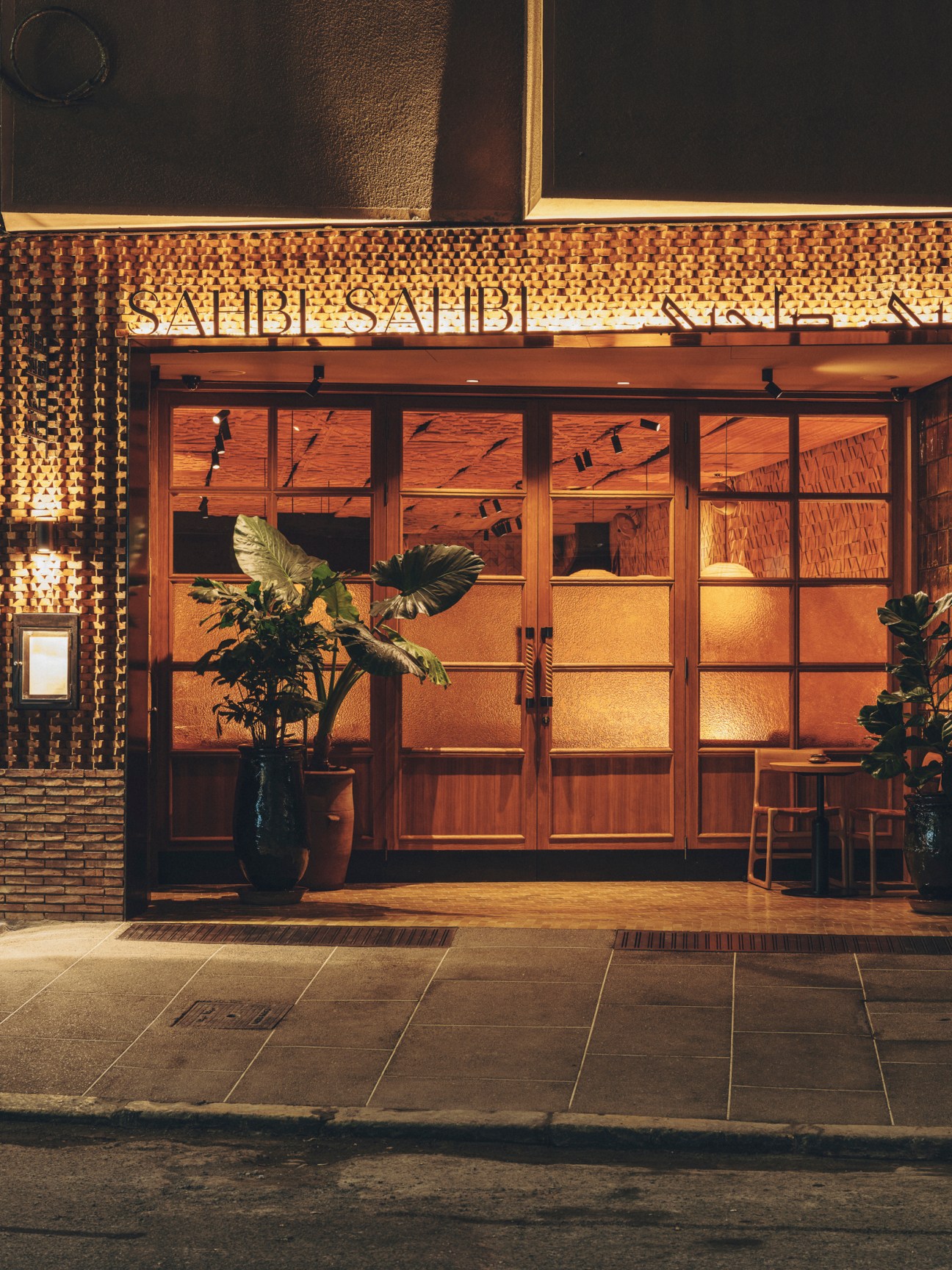 Restaurant entrance with traditional Moroccan tiled facade, large windows, and warm interior lighting at night