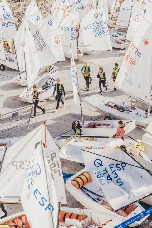 Sailboats with numbered markings lined up on a waterfront in San Sebastián, Spain.