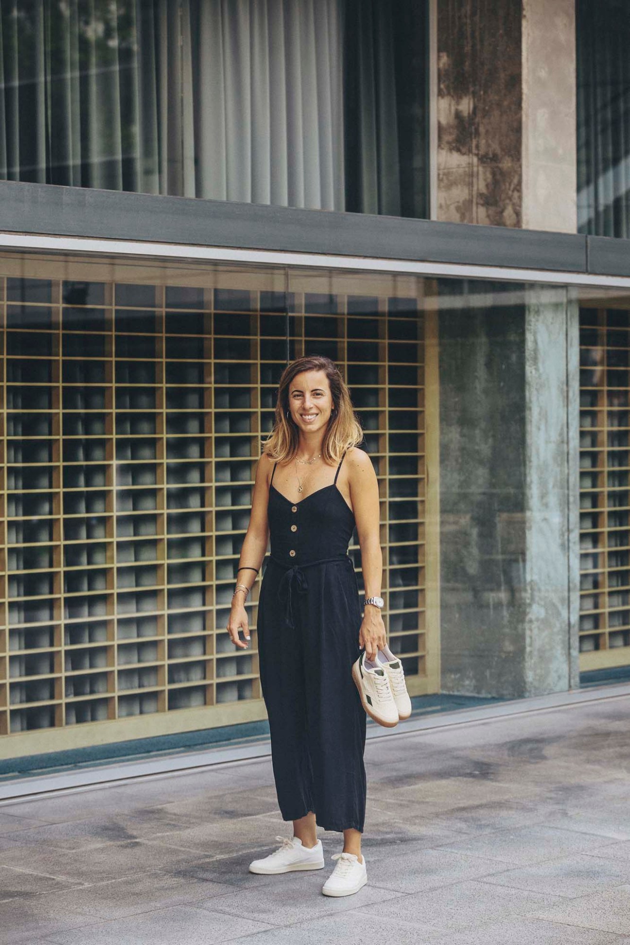 Marta Llaquet, founder of Saye, standing in front of a modern building with gridded windows