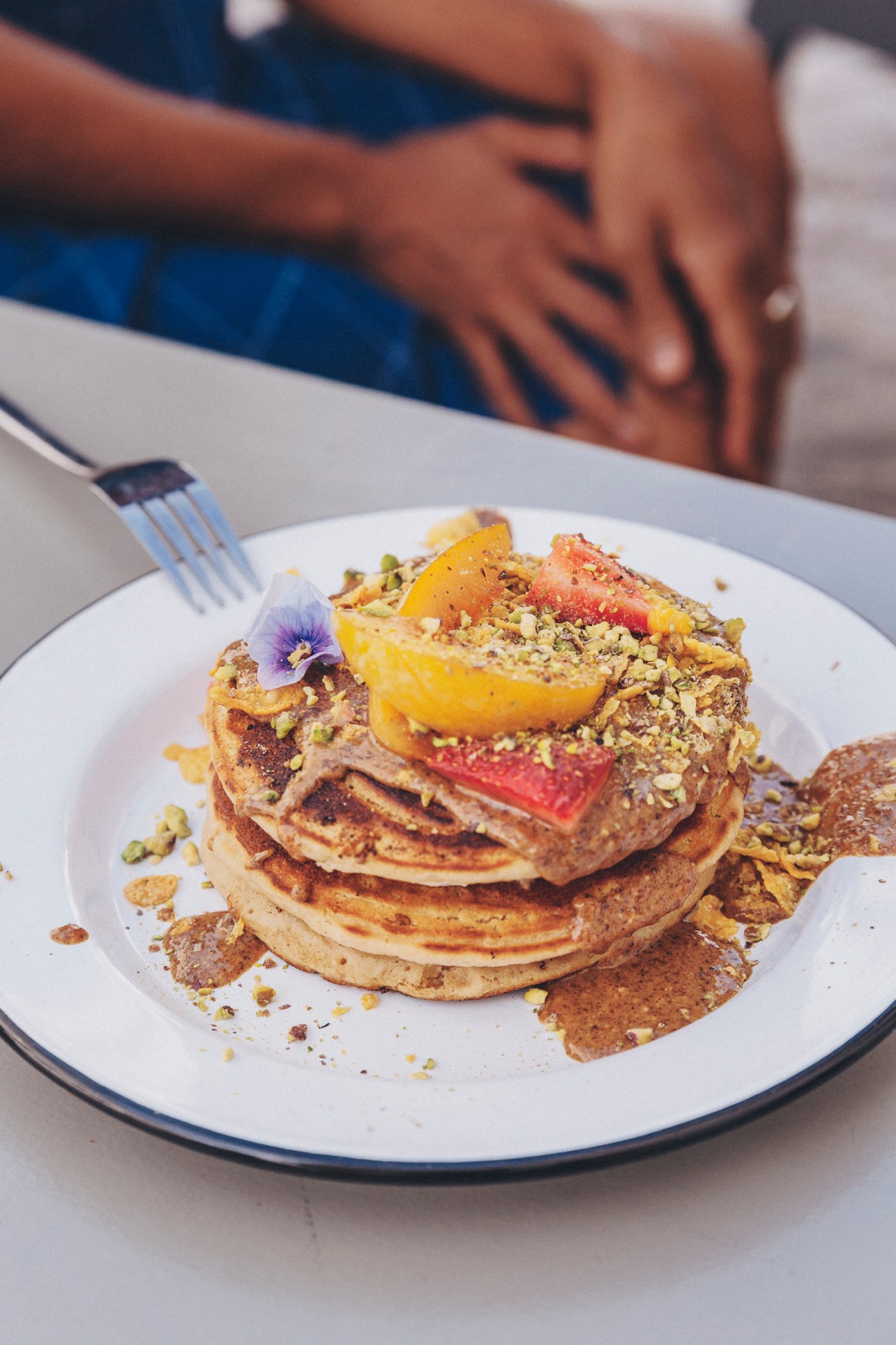 Stack of vegan pancakes topped with fruit and pistachio crumbs at Bonjour Café.