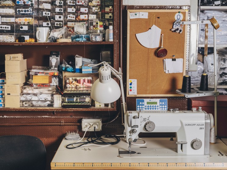 Durkopp Adler 281 sewing machine with adjustable lamp at cluttered workshop station with shelves of supplies