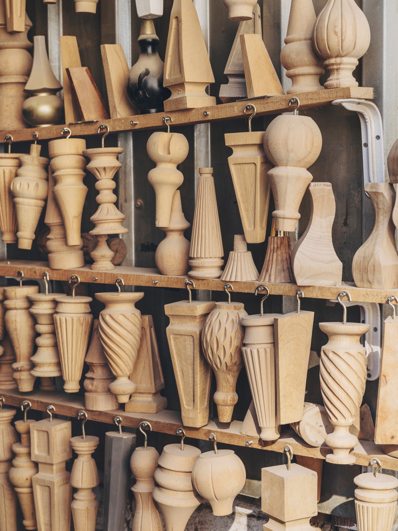 Wooden furniture components and table legs hanging on display racks in a workshop