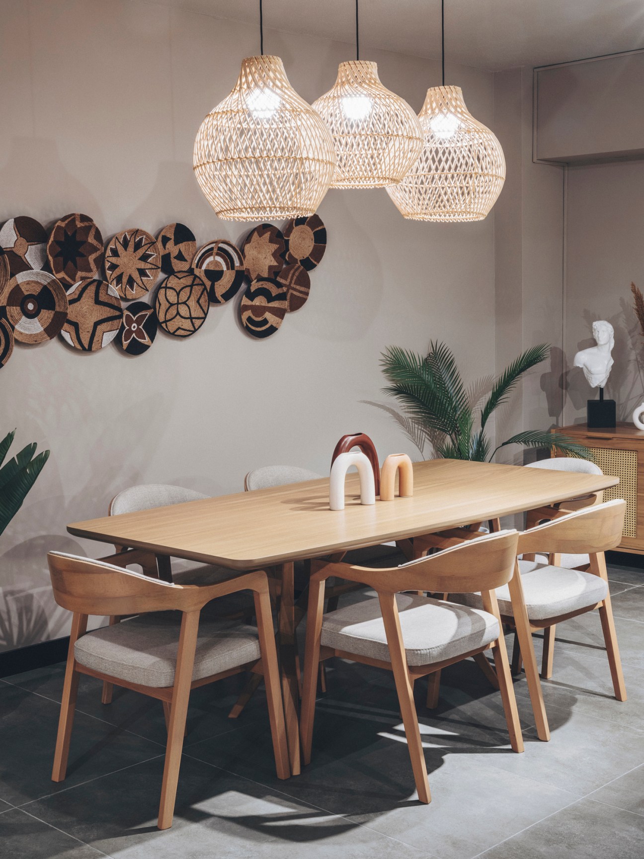 Modern dining room with wooden table, chairs, woven pendant lights and decorative wall art in Vivense showroom