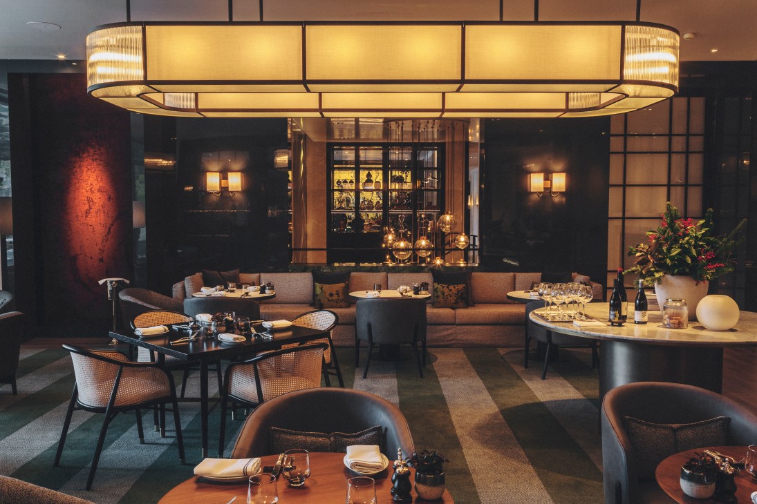 Las Brasas de Castellana restaurant interior with warm lighting, round tables, upholstered chairs and open kitchen