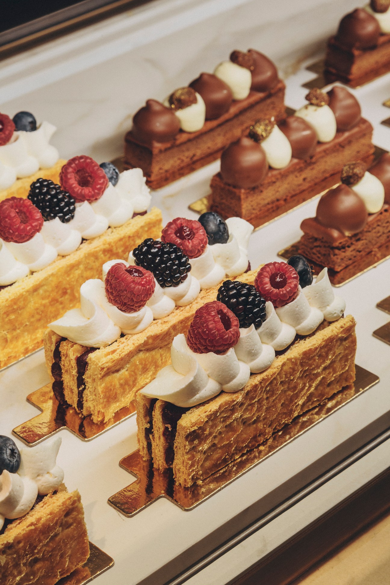 Elegant pastries with chocolate spheres, white cream dollops and fresh berries displayed on rectangular plates