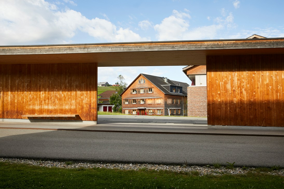 Modern angular wooden bus shelter with distinctive geometric design in rural Austrian setting
