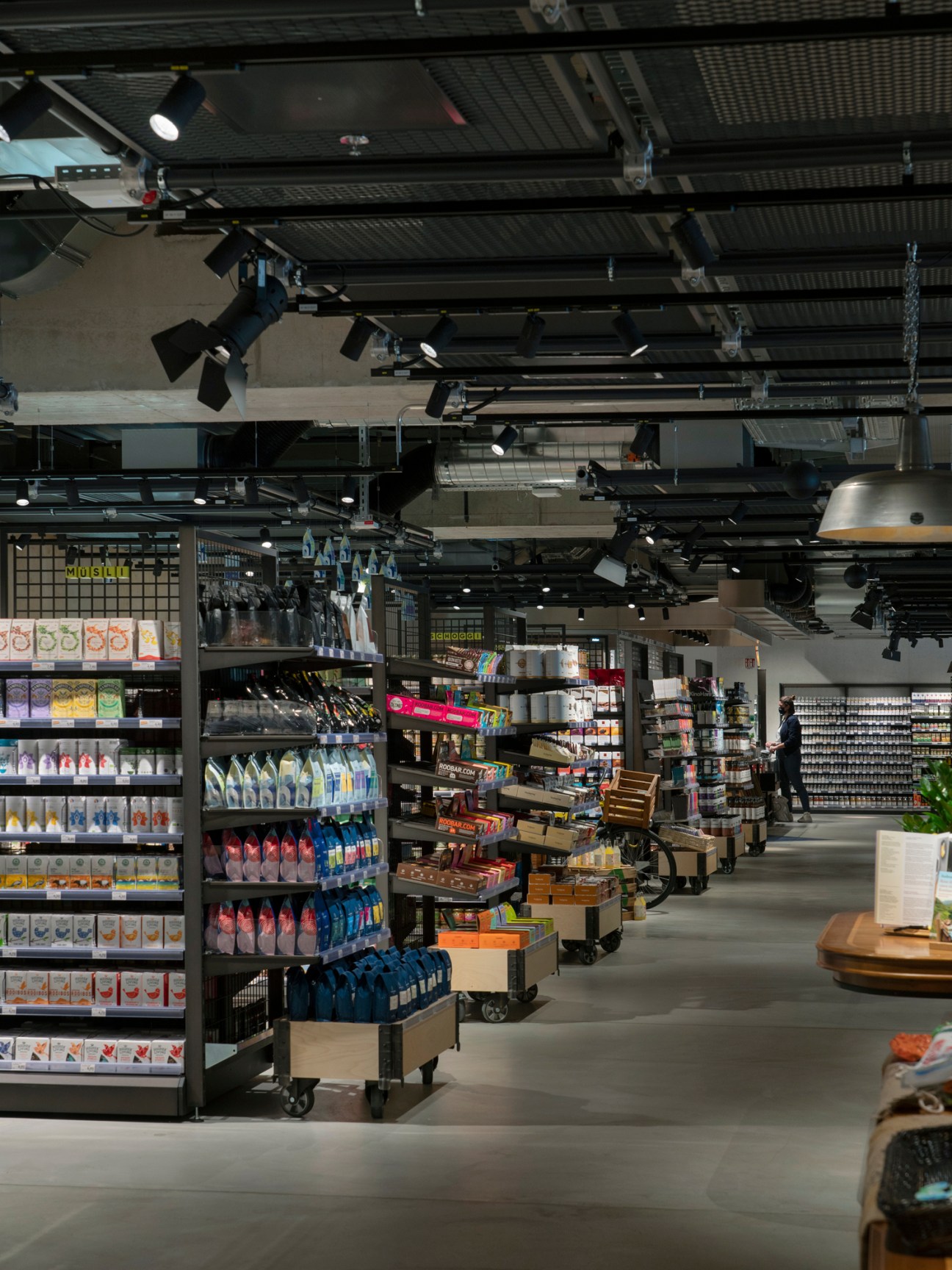 Interior view of modern supermarket with shelves of products, exposed ceiling, and industrial lighting