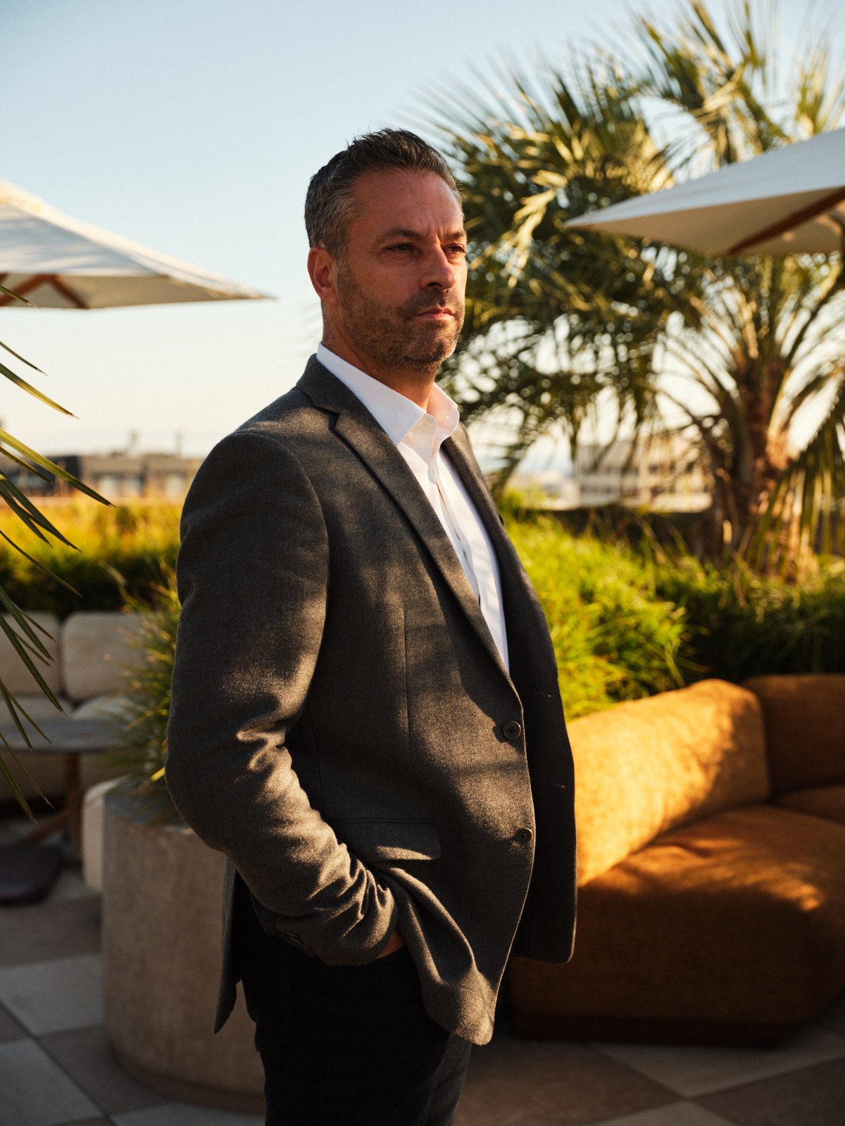 Stephane Lacroix, general manager of Downtown LA Proper Hotel, stands on a terrace overlooking palm trees and umbrellas.