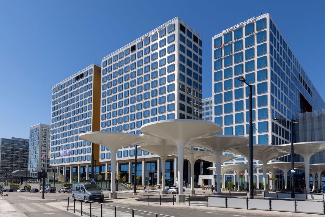 Modern railway terminal building with curved white canopy structure and glass office towers