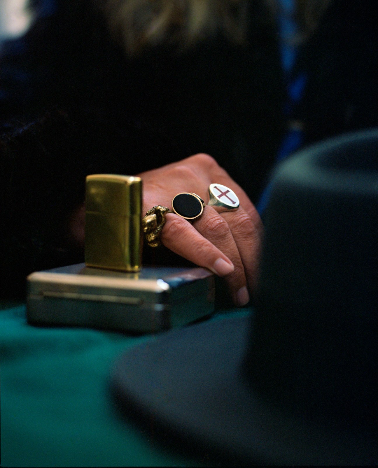 Close-up of hands wearing multiple rings including one with Saint George's cross, holding a golden lighter