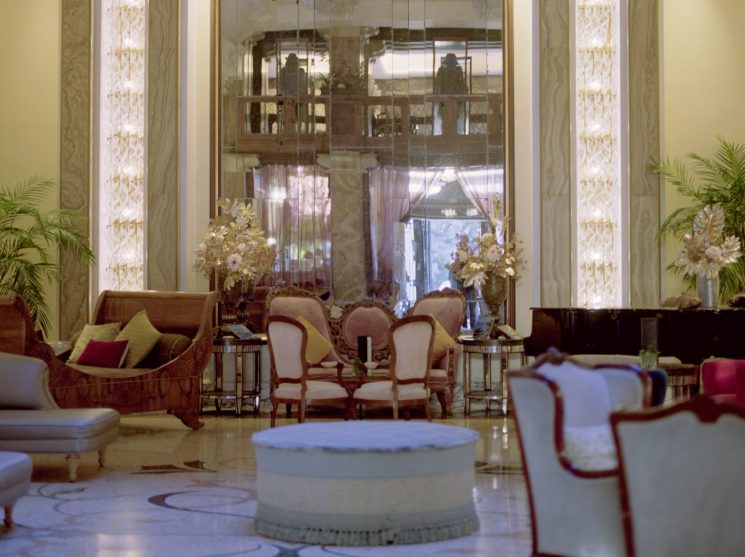 Elegant hotel lobby with marble columns, crystal chandeliers, ornate ceiling details and classic furniture