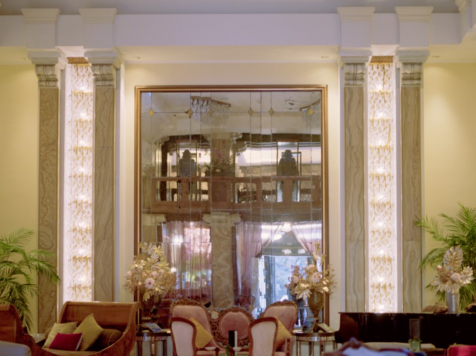 Elegant hotel lobby with marble columns, crystal chandeliers, ornate ceiling details and classic furniture