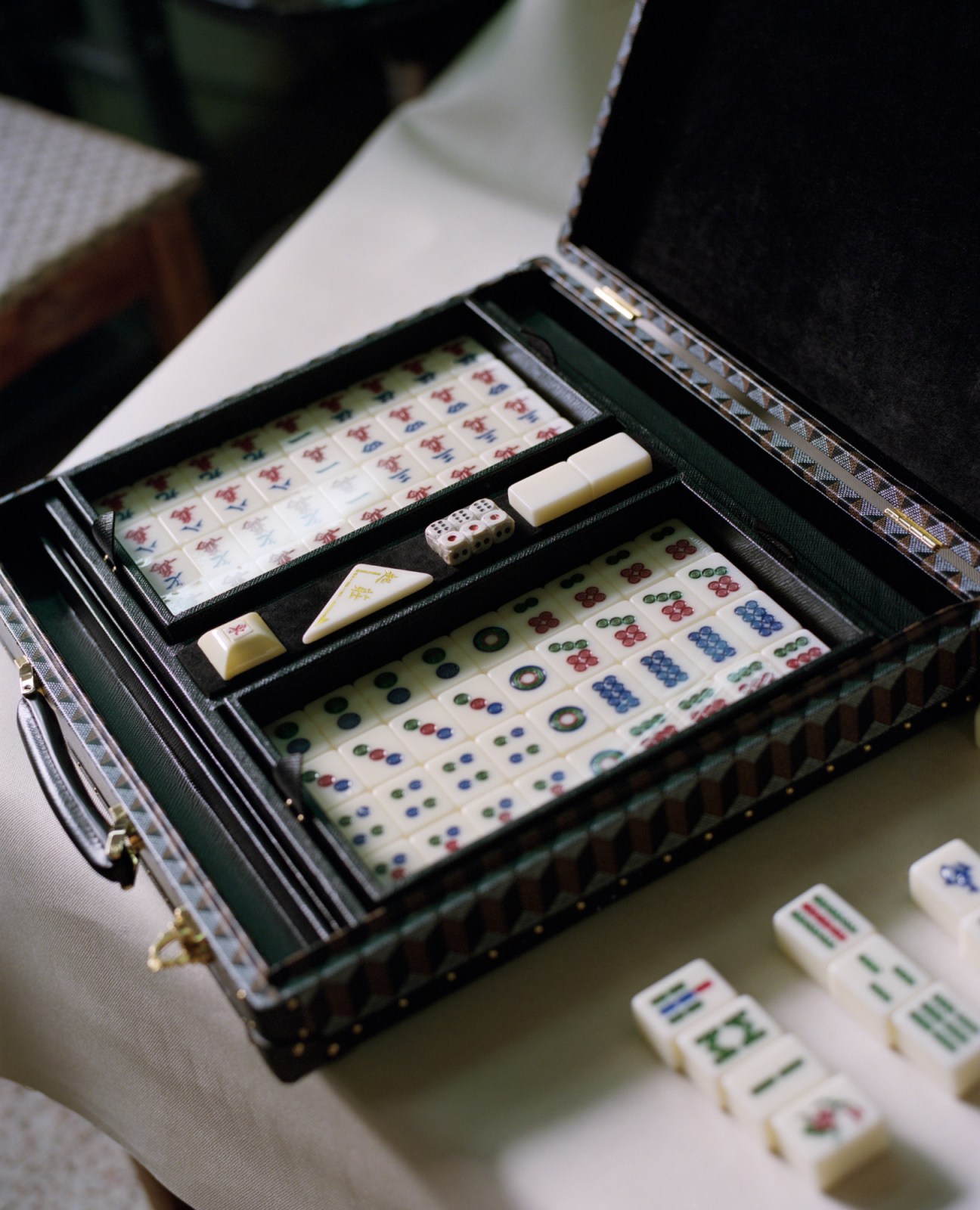 Open case containing mahjong tiles with white pieces and colorful dots and symbols in organized compartments