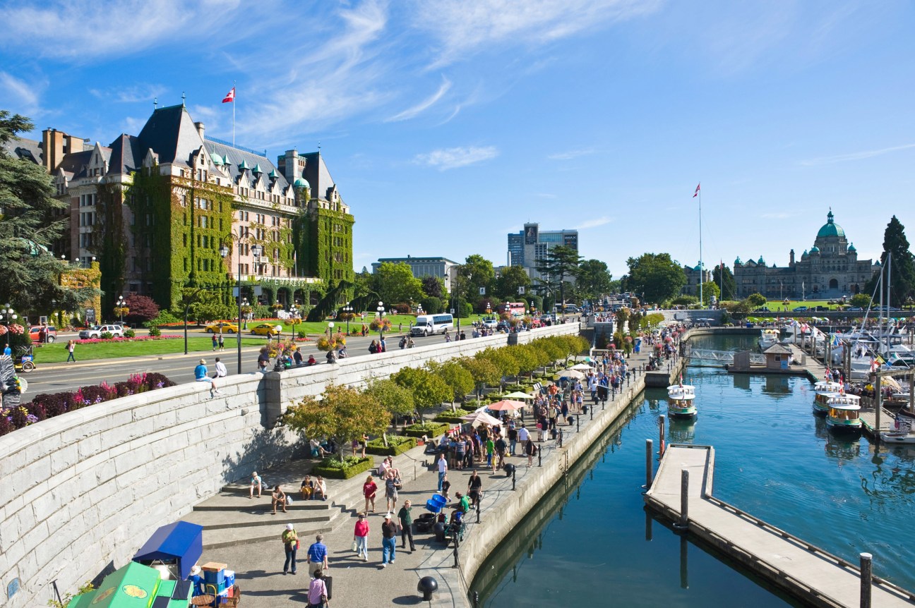 Victoria's Inner Harbour with historic Fairmont Empress Hotel, waterfront promenade, boats, and British Columbia Parliament building.