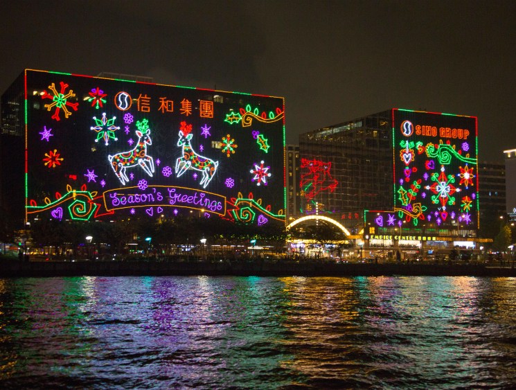 Hong Kong waterfront buildings lit up with colourful Christmas decorations at night.