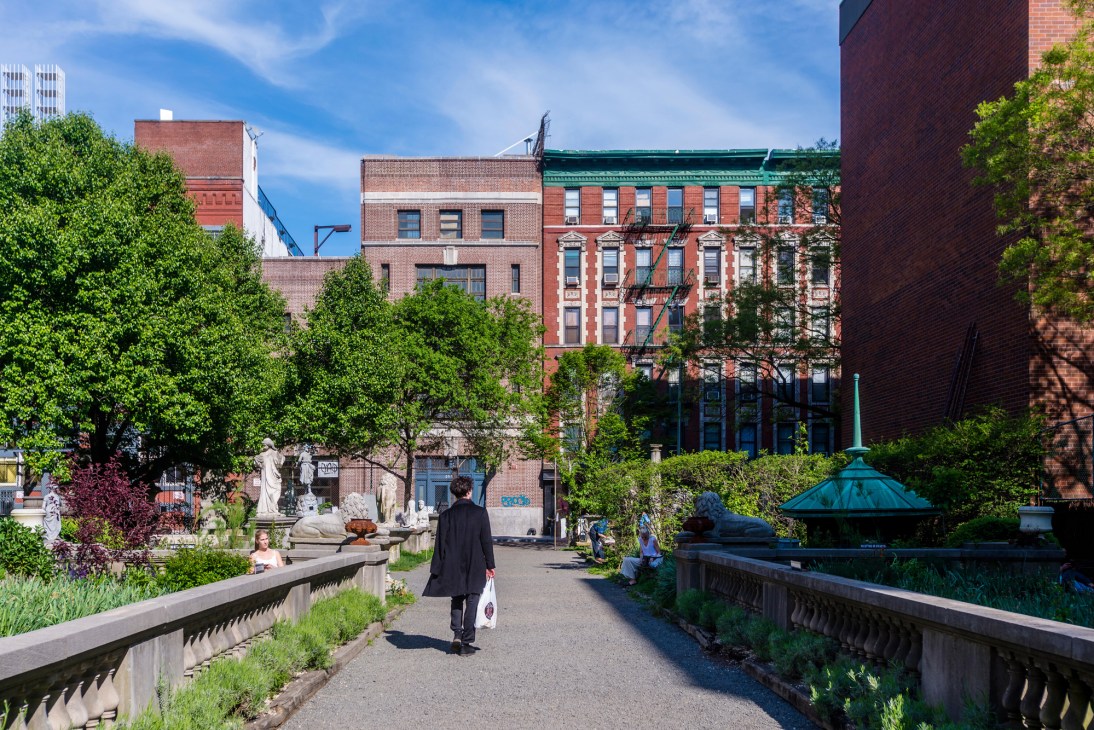 Elizabeth Street Garden with stone sculptures and monuments among greenery in Manhattan