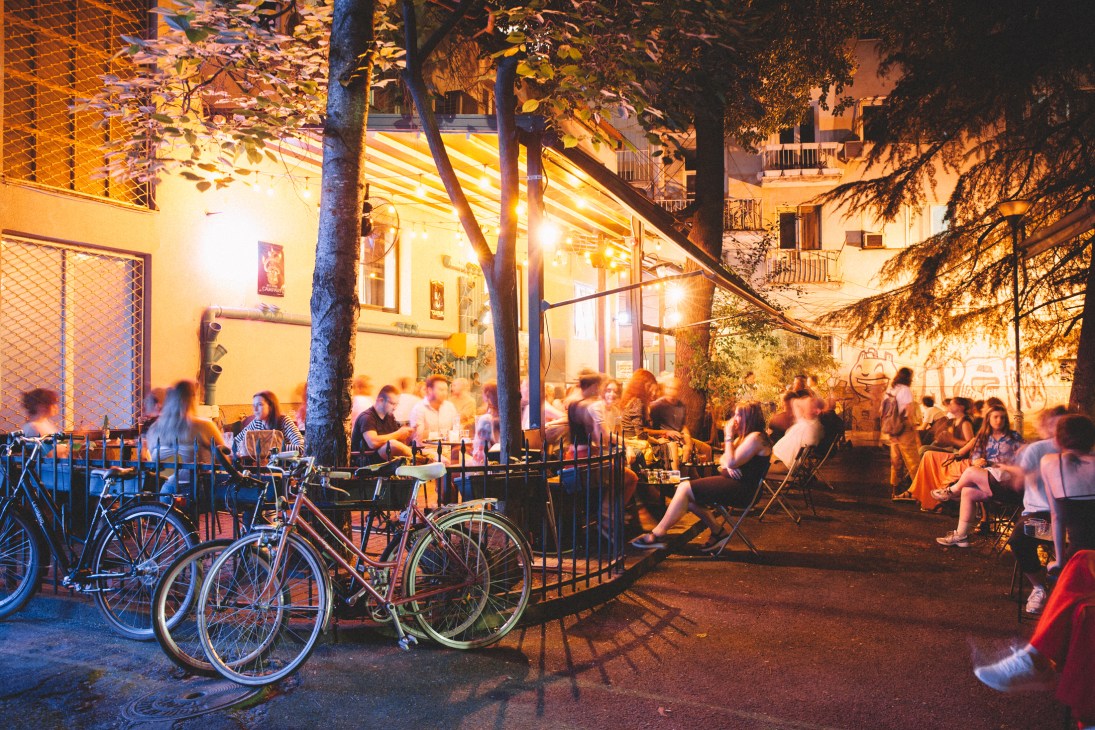 Evening exterior view of Café Kotur with warm lighting and people gathered outside